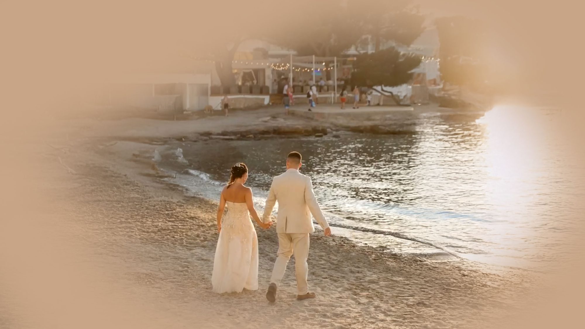 Pareja recién casada caminando por la playa al atardecer en Cala de Bou, Ibiza